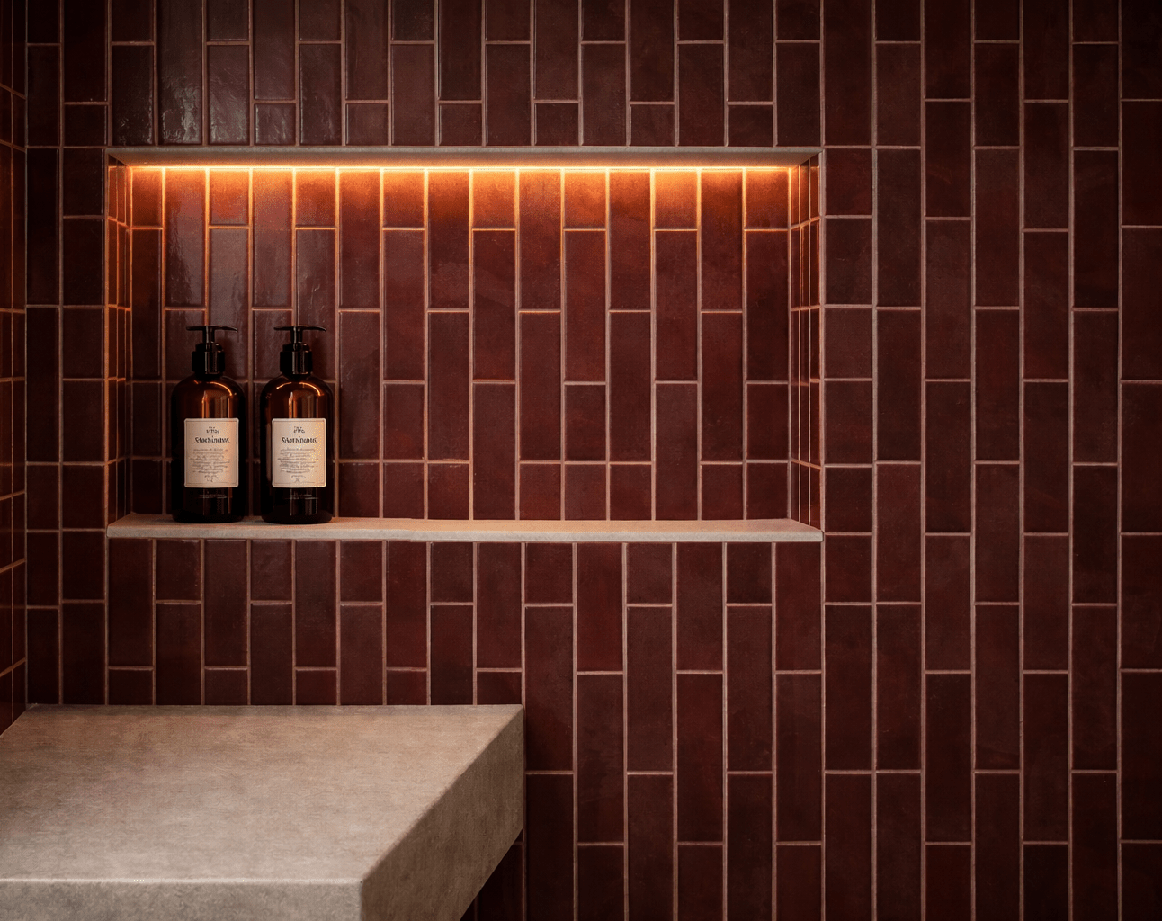 détail de niche rétroéclairée en zellige bordeaux avec banc maçonné en béton ciré. Exemple de rénovation de salle de bain soignée